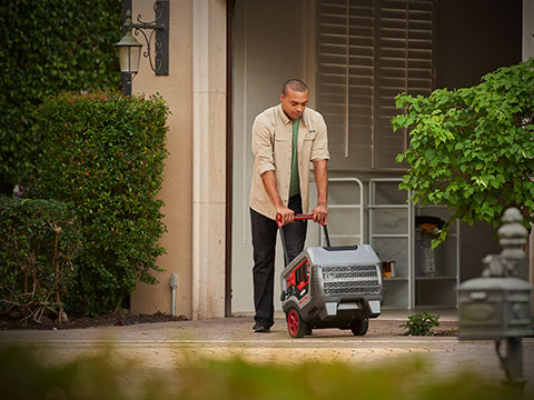 Man pushing QuietPower™ series inverter generator out of a garage