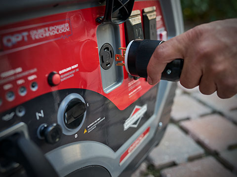 Person plugging cord into QuietPower™ series inverter generator outlet