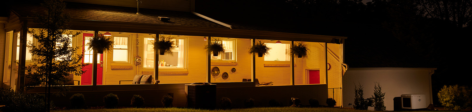 Standby generator in front of lit house at night.