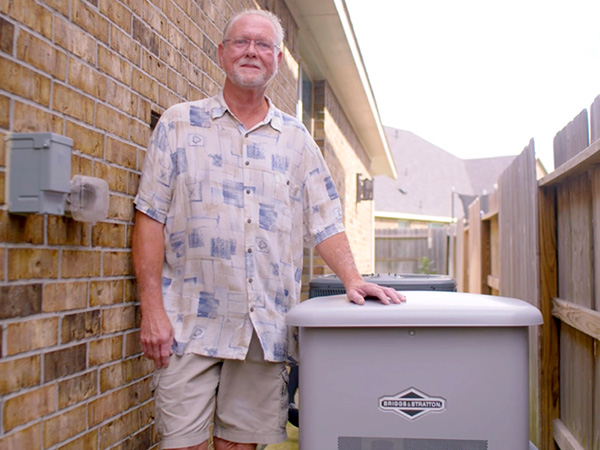 Tim Theiss standing next to his home and standby generator. 