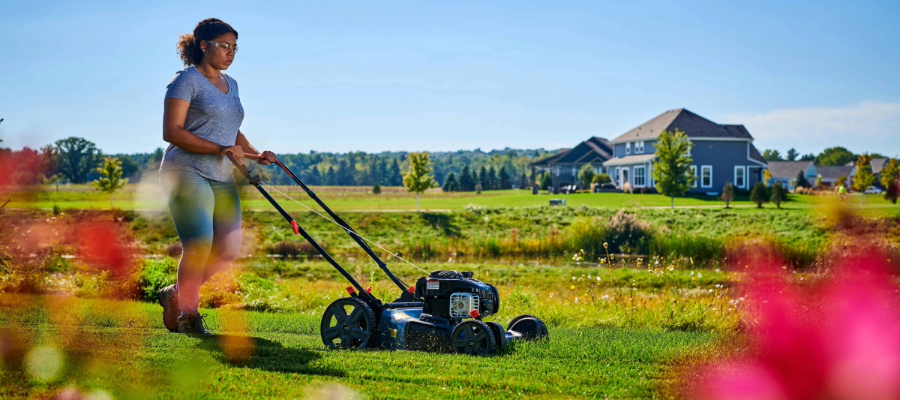 Woman mowing her lawn with a walk-behind mower powered by a Briggs & Stratton engine.