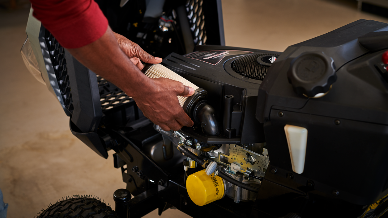 A man servicing a Briggs &amp; Stratton ride mower engine.