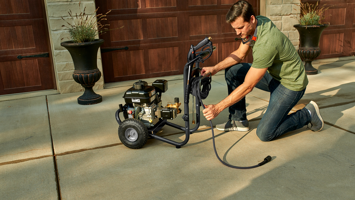 Man wrapping up a cord for a gas pressure washer powered by a Briggs &amp; Stratton Single-Cylinder Horizontal Shaft utility engine