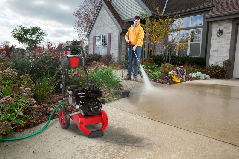 A man outside his home power washing his driveway using a pressure washer powered by a Briggs & Stratton CR950 single-cylinder horizontal shaft utility engine.
