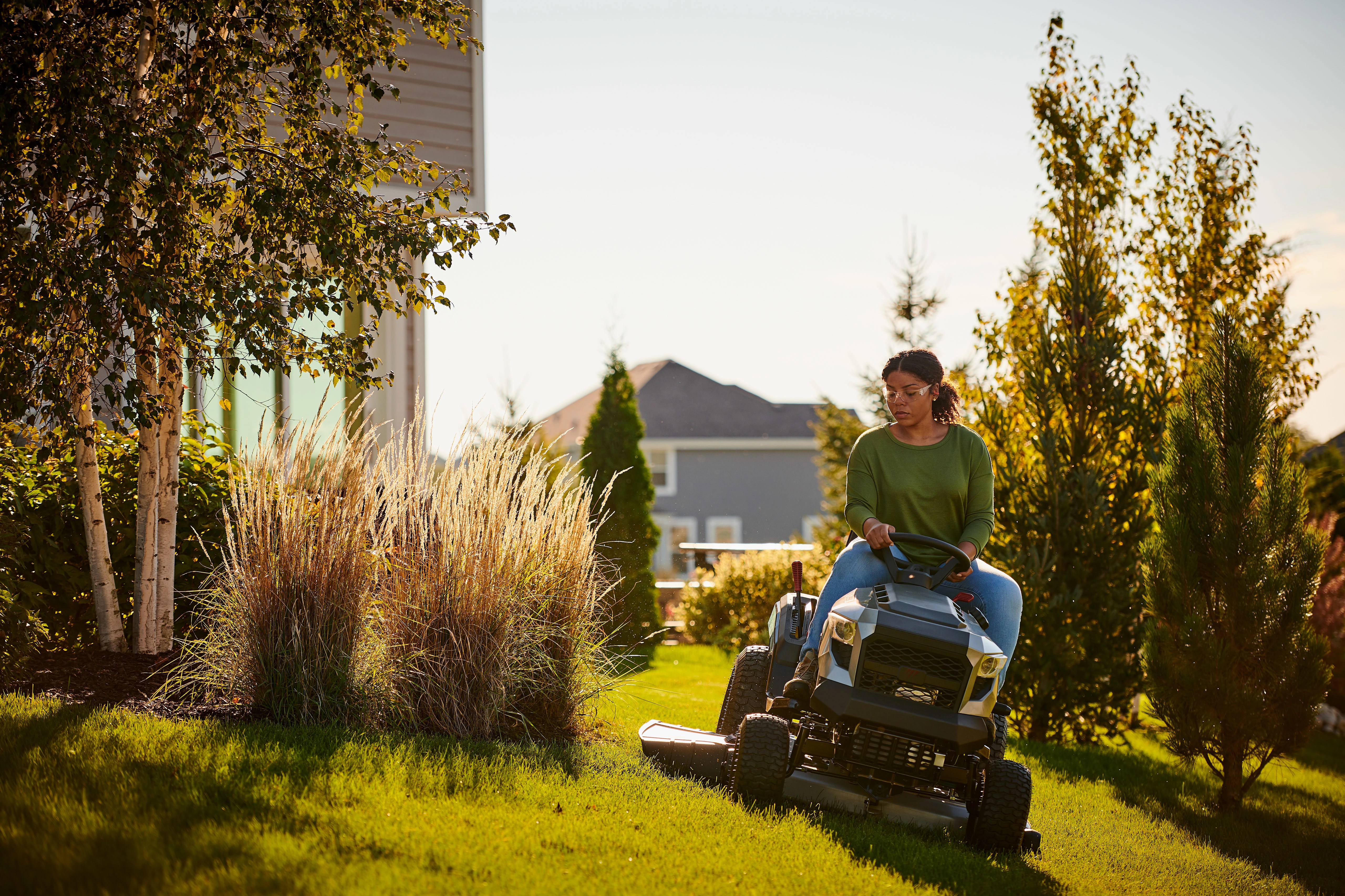 Woman comfortably mowing her lawn with a Murray riding mower powered by Briggs & Stratton.