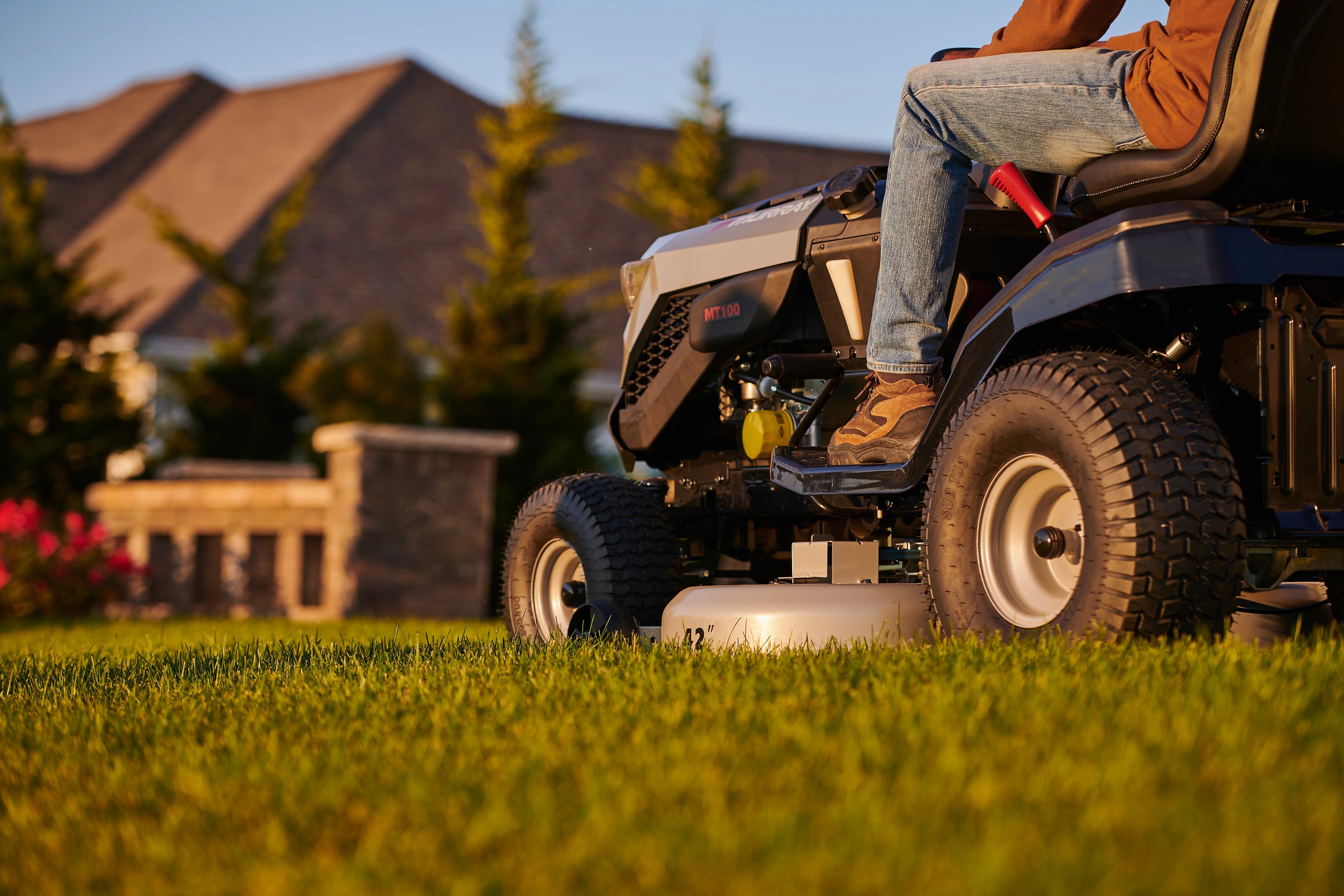 Close-up side view of a Murray riding lawn mower in action, highlighting the 42-inch cutting deck and Briggs & Stratton engine compartment